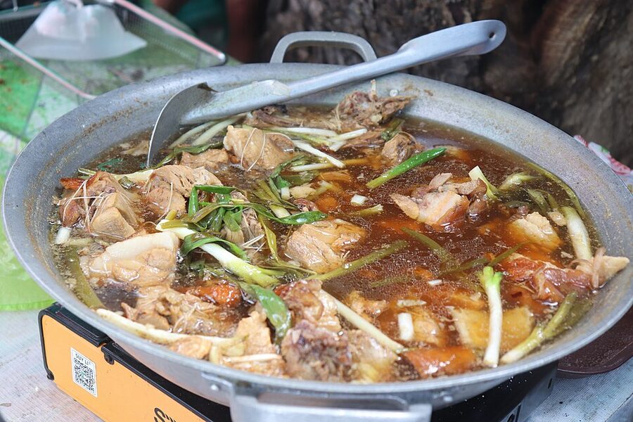 Lechon paksiw simmering in a wok, the leftover-pork dish