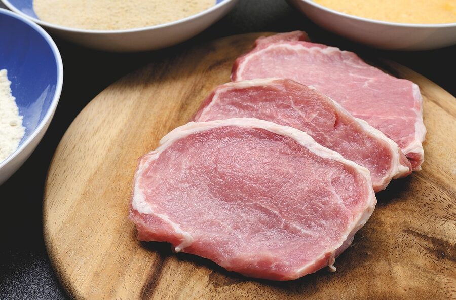 Raw pork belly steak, scored and ready for stuffing