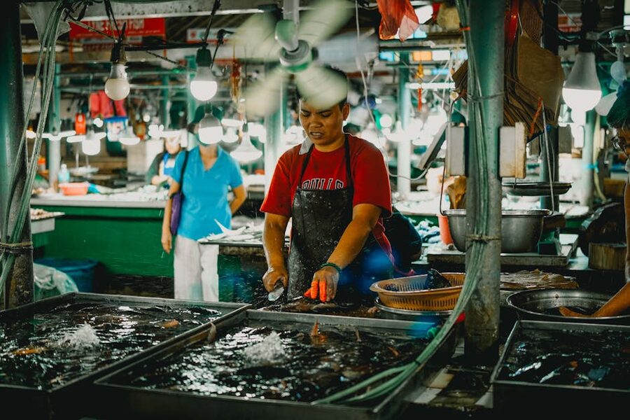 A fishmonger preparing seafood at a market stall